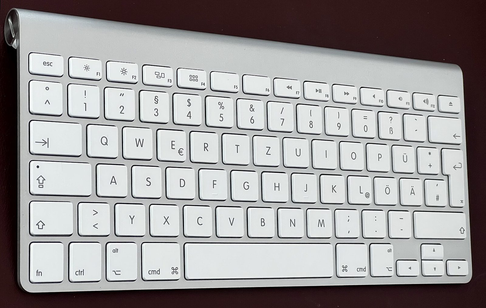 An Apple Wireless Keyboard from 2011. A cylindrical battery tube runs along the top edge.