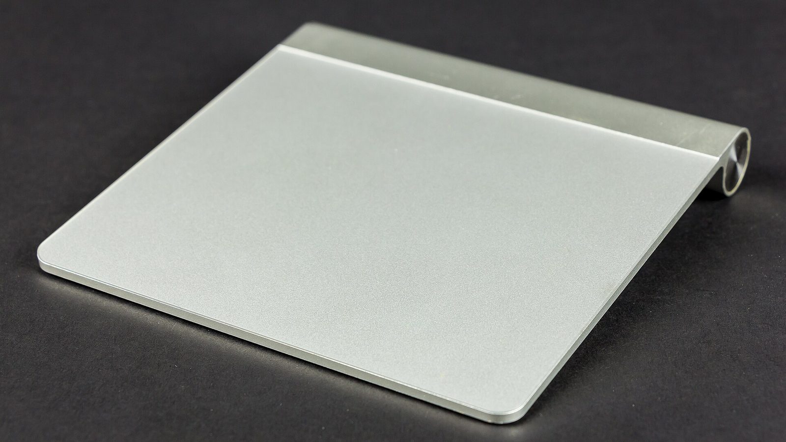 A Magic Trackpad from 2010. A round cap on the back edge unscrews to reach the AA batteries.
